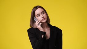 4k video of one girl talking over the phone on yellow background.