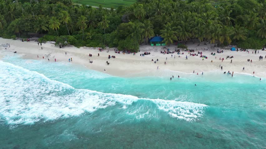 Aerial view of people on the beach along the shoreline on Maldives Islands.