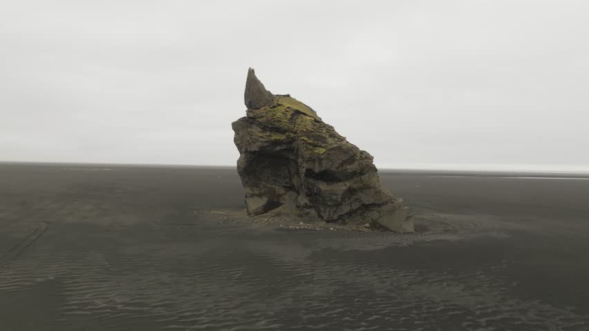 Aerial view of a car driving toward a rock formation in a valley in Iceland Highlands.