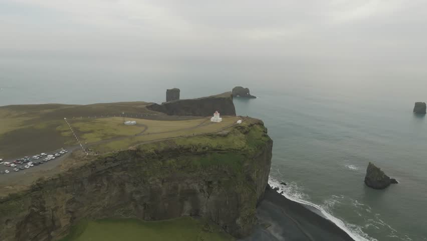 Aerial view of a lighthouse at Dyrholaey cliff along the coastline, Iceland.
