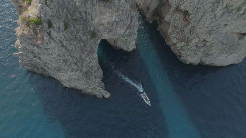 Aerial view of sailing boat cruising near the Faraglioni rock formation off Capri Island, Naples, Italy. Royalty-Free Stock Footage #1101287885