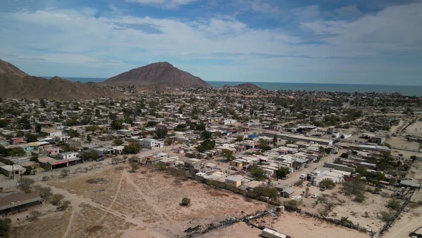 Wide aerial panning over neighborhoods in town of San Felipe Baja California Mexico in desert mountains and view of Sea of Cortez
