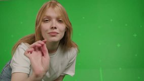 Close-up of Attractive red-haired white girl swipes finger at display of phone. Young woman in jeans and knitted jumper in a positive mood over green screen background, Chroma Key. 4k video footage - Powered by Shutterstock - Get 15% off with code: PIKWIZARD15