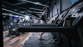 Sports man runs on a treadmill, doing fitness. Athletic and muscular man is actively training in a modern gym. Sports people exercising. slow motion - Powered by Shutterstock - Get 15% off with code: PIKWIZARD15