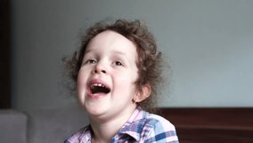 Close-up Portrait of Happy Little Child Girl Bursting in Laugh. Kid Laughs Indoors at home. Looking to Camera