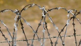 Fence with Sharp Razor Wire Blades. Concertina wire close-up. Pan from left. - Powered by Shutterstock - Get 15% off with code: PIKWIZARD15
