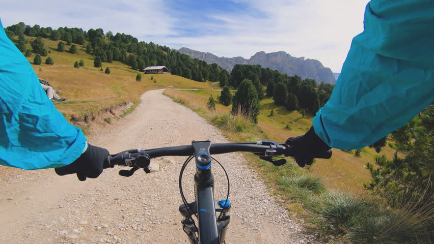 POV shot man with mountain bike cycling down Seceda mountain on dirt road. Puez Odle, Trentino, Dolomites, Italy. Royalty-Free Stock Footage #1101319139