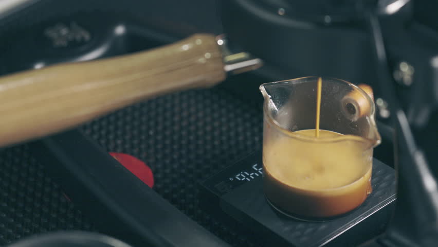 Close up slow motion 4K of beautiful coffee liquid flowing from coffee machine into clear glass on barista counter in coffee shop shows concept of enjoyment beverage for breakfast in the morning. | Shutterstock HD Video #1101320615