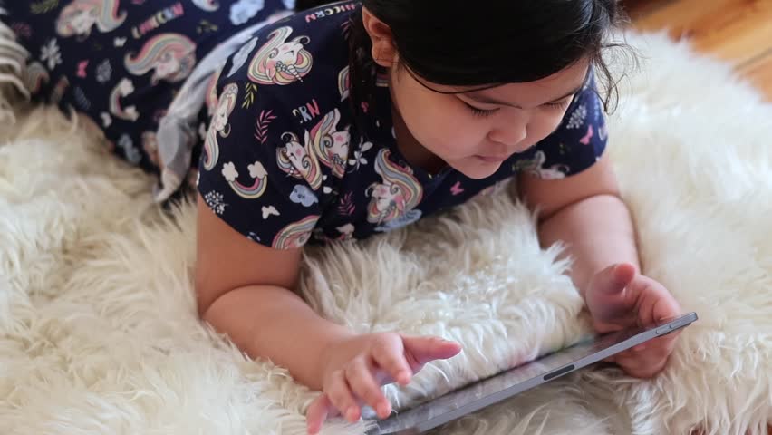 Asian child playing and watching shows on a tablet digital computer