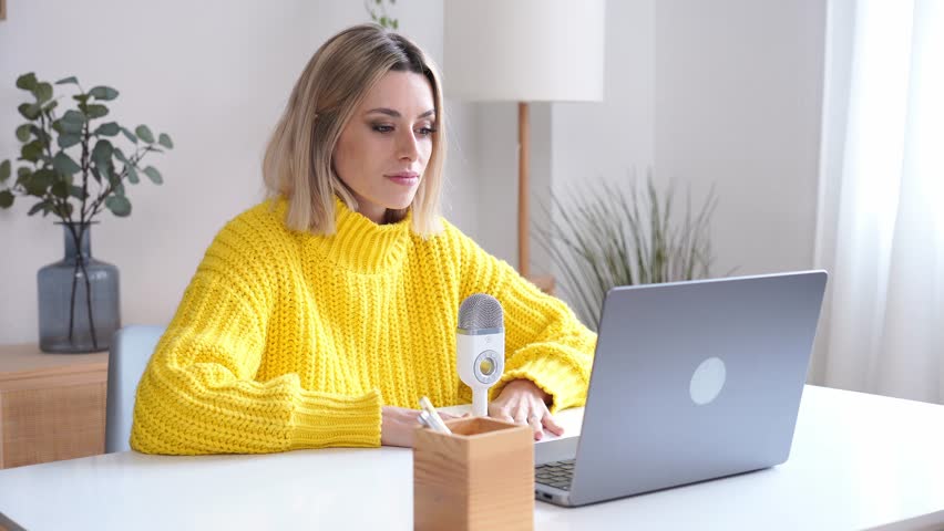 Young woman with laptop recording podcast