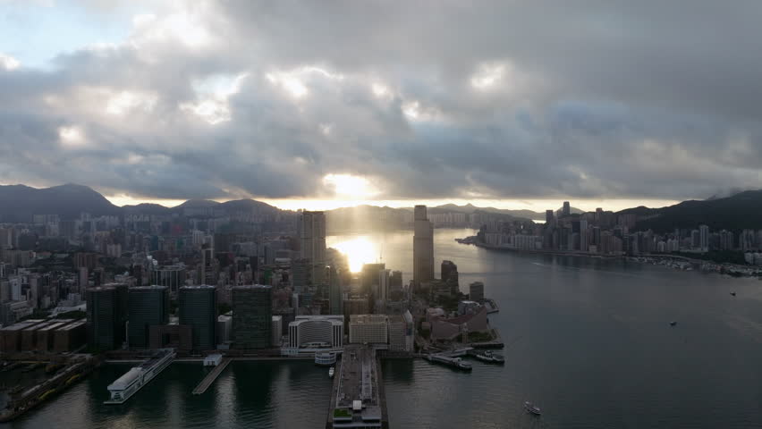 Sun rays through the clouds, behind Tsim Sha Tsui in Hongkong on a cloudy day. Aerial drone panning shot