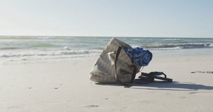 Video of bag with beach equipment lying on sand on beach. Holidays, vacations, relax and summer concept.