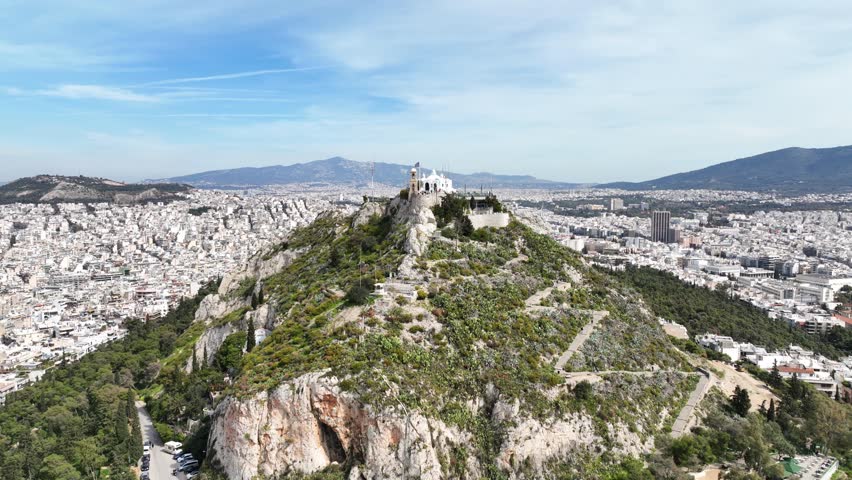 Aerial drone cinematic video of Athens cityscape and iconic chapel of Saint George on top of Lycabettus hill with beautiful deep blue sky, Athens, Attica, Greece Royalty-Free Stock Footage #1101335521