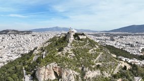 Aerial drone cinematic video of Athens cityscape and iconic chapel of Saint George on top of Lycabettus hill with beautiful deep blue sky, Athens, Attica, Greece