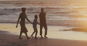 Video of happy african american family walking on beach at sunset. Holidays, vacations, relax and spending quality family time on beach.