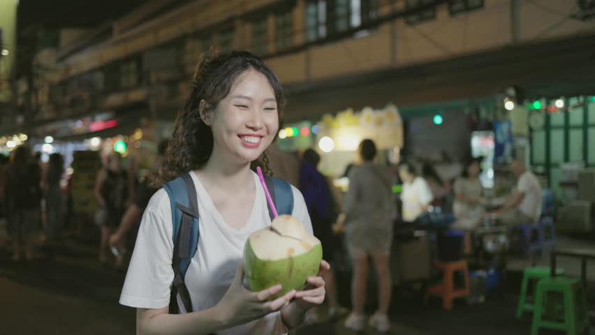 Asian young female traveler buys street food at Khao San Road night market, bangkok, thailand, savoring the flavors and enjoying the lively atmosphere. nightlife concept Royalty-Free Stock Footage #1101338679