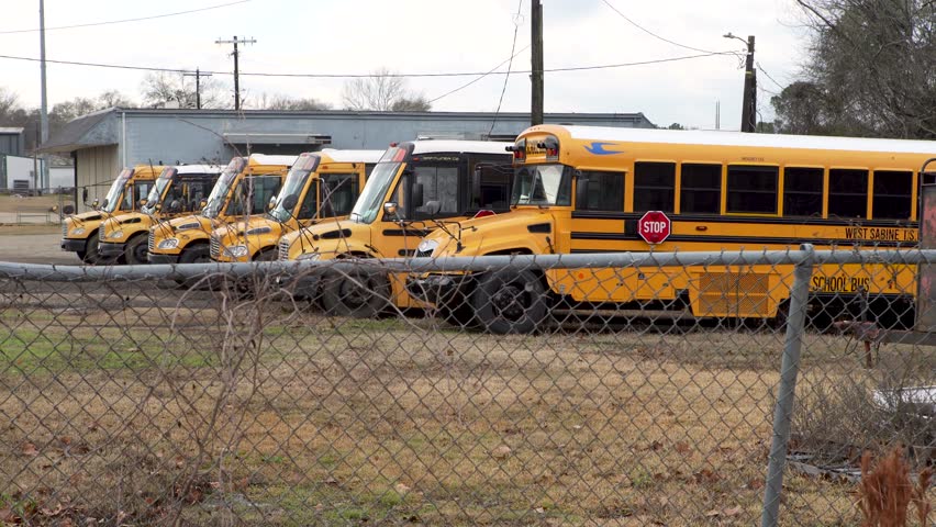 Pineland, TXUSA - Jan. 8, 2023 West Sabine Independent School District buses sit in a lot surrounded by a chain link fence.  | Shutterstock HD Video #1101338973