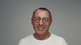 Portrait of Adult Man in Old Glasses Looks at Camera in Color Studio Shot. Older Male Isolated Alone on White Background Close-up. Headshot of Aged Joyful Person turns Head and Smiles with Happy Face - Powered by Shutterstock - Get 15% off with code: PIKWIZARD15