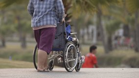 Rear view of Wheelchair helper view sharing elderly people walking in the park
