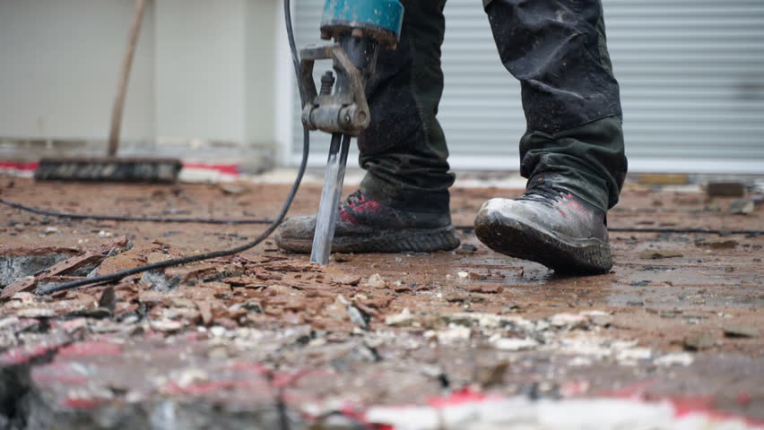 A construction worker using a jackhammer to remove old concrete near the house - close-up Royalty-Free Stock Footage #1101343891
