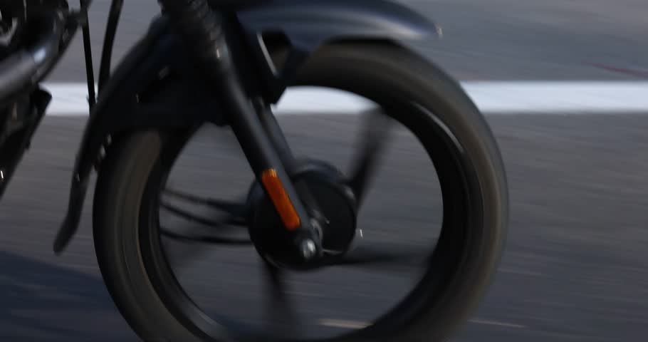 Slow-motion footage of a motorcycle wheel moving at high speed on an asphalt road. The black tire of the motorcycle is in contact with the asphalt. Two-wheeled transportation is a popular choice for .