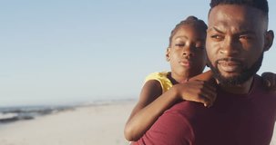 Video of african american father wearing piggyback daughter on beach. Holidays, vacations, relations and spending quality family time together concept.