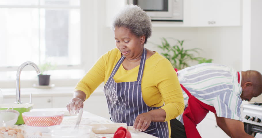 Happy african american senior couple baking together in kitchen, slow motion. Family, cooking and togetherness concept. Royalty-Free Stock Footage #1101345079