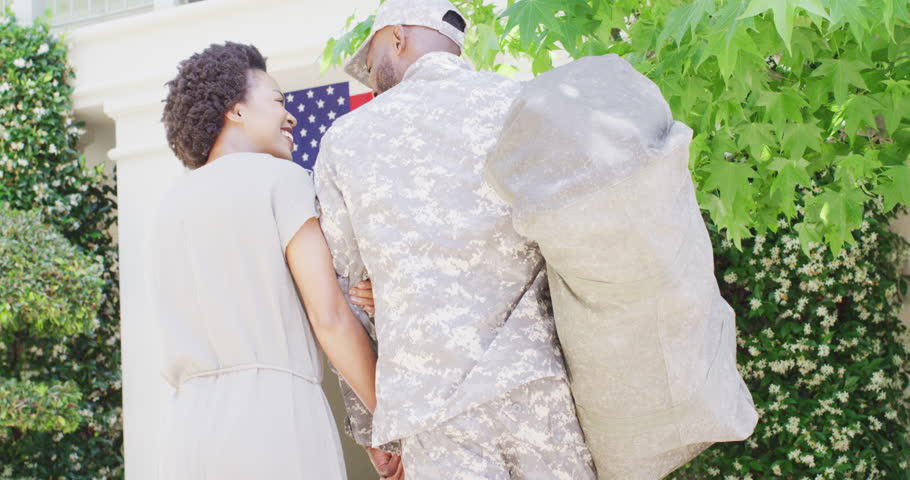 African american male soldier returning home, greeted by happy wife, slow motion. Family, military service and homecoming concept.