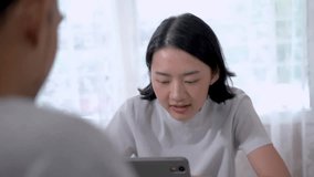 Asian woman talking to colleague team. Woman sketching ideas on smart tablet to present new project. Work from home concept with new technology.