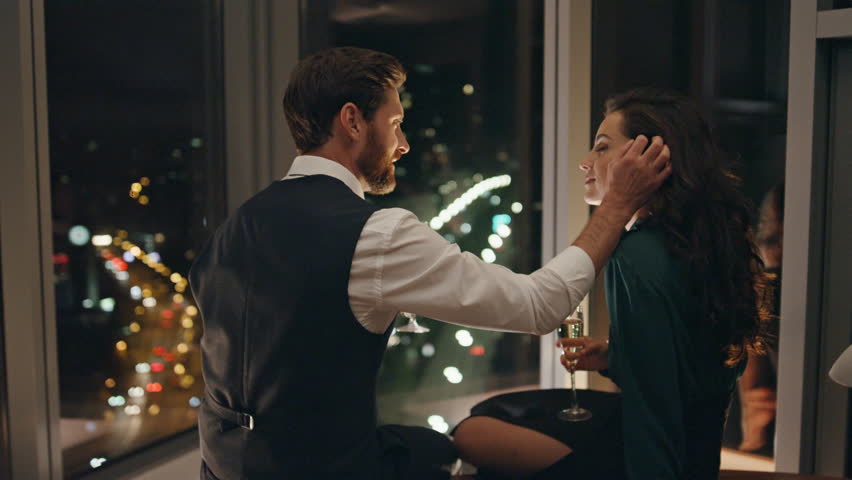 Confident bearded man seducing woman sitting at panoramic window late evening. Handsome seducer flirting with attractive brunette girl. Romantic happy couple relaxing enjoying date drinking champagne. Royalty-Free Stock Footage #1101358889