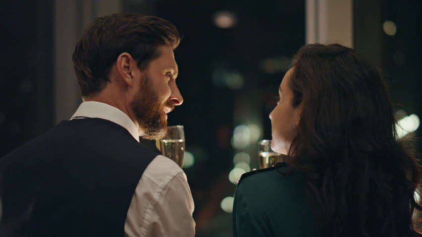 Smiling happy couple enjoy romantic evening with champagne standing at window close up. Young lovers relaxing drinking alcohol together. Bearded man flirting with brunette woman enjoying lovely date. Royalty-Free Stock Footage #1101358967