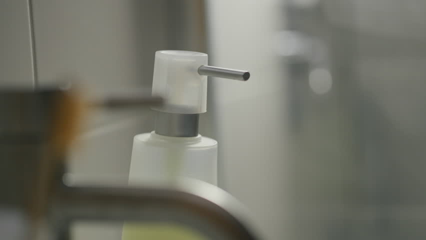 A person pressing the dispenser to release liquid soap and wash their hands, maintaining proper hygiene through liquid soap and dispenser, a close-up of soap being dispensed onto palms
 | Shutterstock HD Video #1101363081