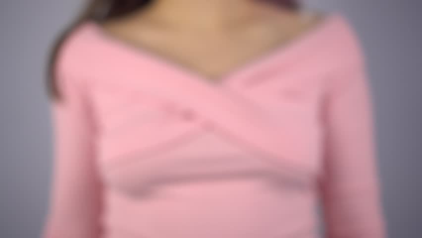 A young woman draws a happy smile on the glass. A girl in a pink sweater draws with a brush and yellow paint. Close-up.