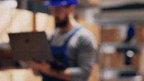 Depot supervisor holding laptop with stock logistics list, looking at merchandise packs and planning order distribution. Male employee using pc to do quality control. Handheld shot. - Powered by Shutterstock - Get 15% off with code: PIKWIZARD15