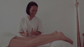 
Slow motion video of a Woman giving a leg massage to a Caucasian girl lying on the massage center massage table.