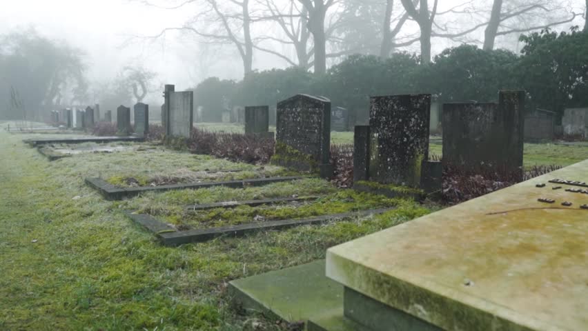 Misty atmosphere at graveyard, camera moves along the grave stones, time passing grieving and sadness concept. Royalty-Free Stock Footage #1101370299