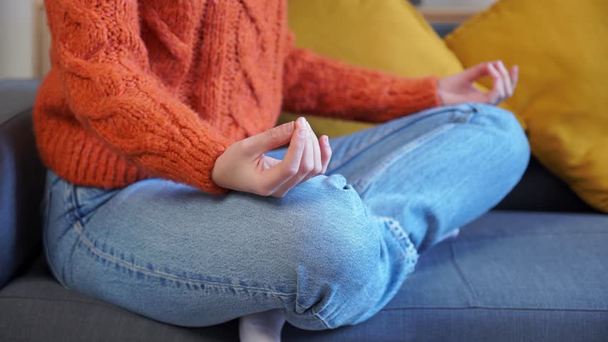 Young woman meditating on sofa