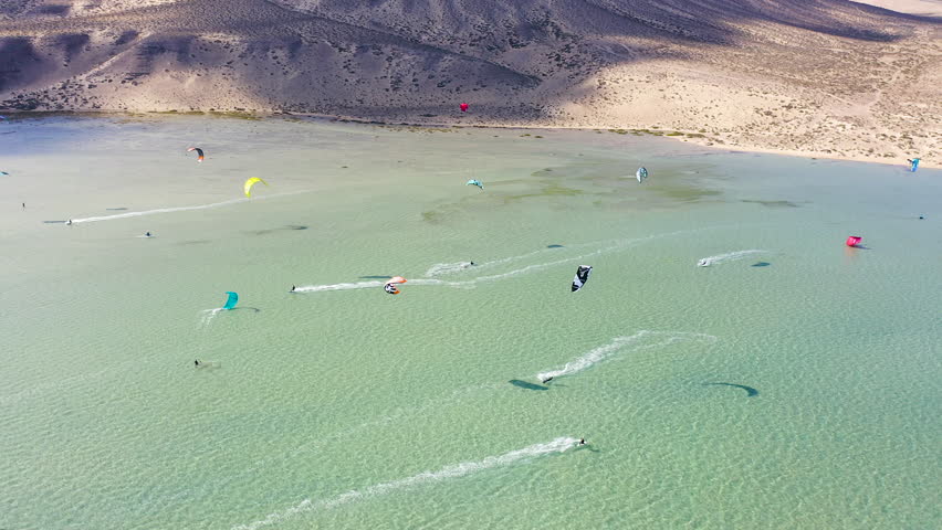 Aerial view of a crowd of kitesurfers enjoying the waves on the beach of Sotavento, Fuerteventura Island, Spain. Royalty-Free Stock Footage #1101375359