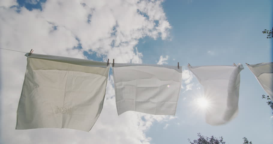 Bed linen hanging on a clothesline and drying against a blue sky Royalty-Free Stock Footage #1101376887