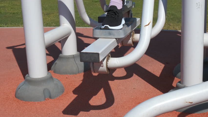 Girl traveler training legs in the park. A young girl fashioned girl training outdoor under sun.