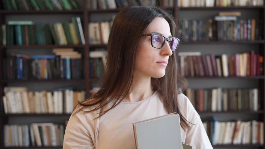 Young smiling cheerful girl college student standing in class campus smiling looking at camera. Close-up portrait.
