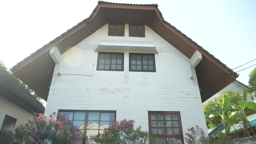 Rear view of happy Asian couple walking towards the front of their new home.