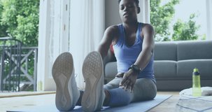 Animation of social media icons and numbers over african american woman exercising at home. Global social media, computing and data processing concept digitally generated video.