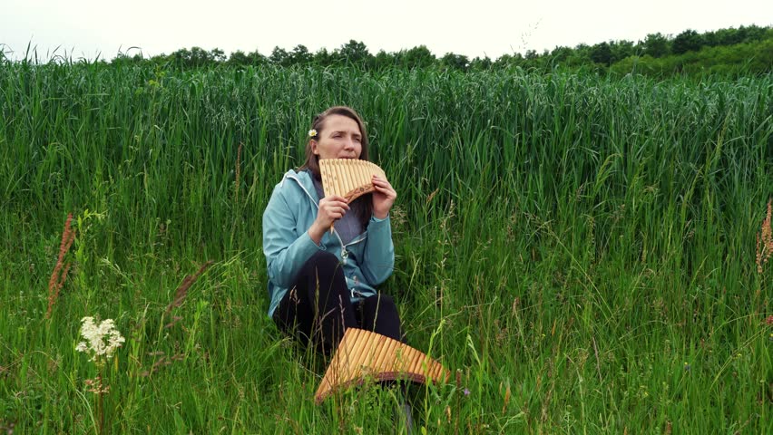 A young woman plays the panflute in nature Royalty-Free Stock Footage #1101384995