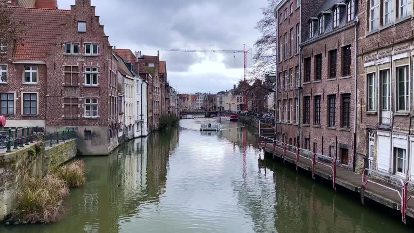 View of the canal, tourist boat and medieval houses of Ghent, a city in the Flemish region of Belgium. Travel concept. High quality 4k footage