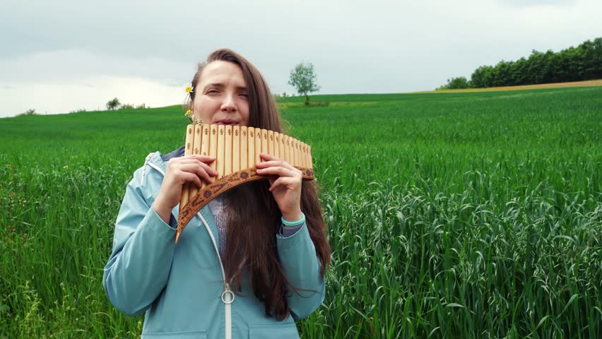 A young woman plays the panflute in nature Royalty-Free Stock Footage #1101388001
