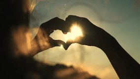 heart sign sunset background. beautiful girl with flowing hair against backdrop sunset sky. love health sign silhouette. Valentine's Day. state mind love. romantic girl glare sun shows heart. concept. - Powered by Shutterstock - Get 15% off with code: PIKWIZARD15