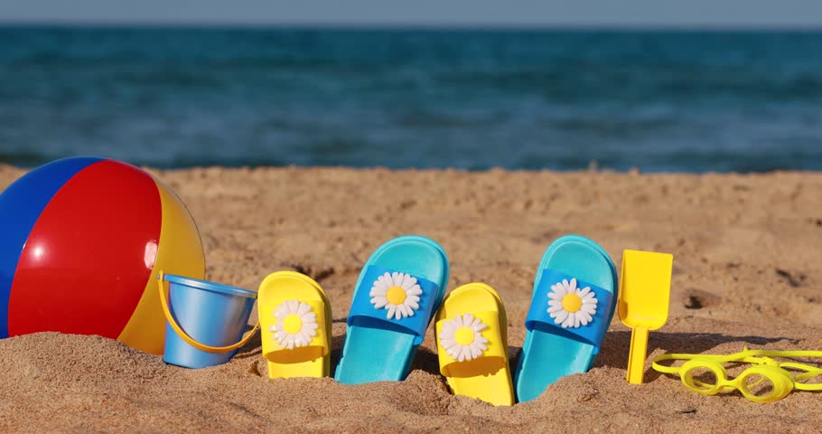 Beach flip-flops on yellow sand against blue sea and sky background. Summer vacation concept. Slow motion | Shutterstock HD Video #1101391943