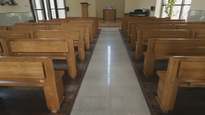 No people shot of small Catholic church interior, camera moving along nave between rows of wooden pews to bema with altar and cross shaped window | Shutterstock HD Video #1101392165