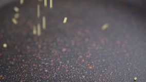 Stream of Falling Yellow Grains of Millet Groats on a Black Surface in Sunlight. Bouncing small round pellets, particles of golden millet in a frying pan. Blurred food background. Couscous. Texture. - Powered by Shutterstock - Get 15% off with code: PIKWIZARD15